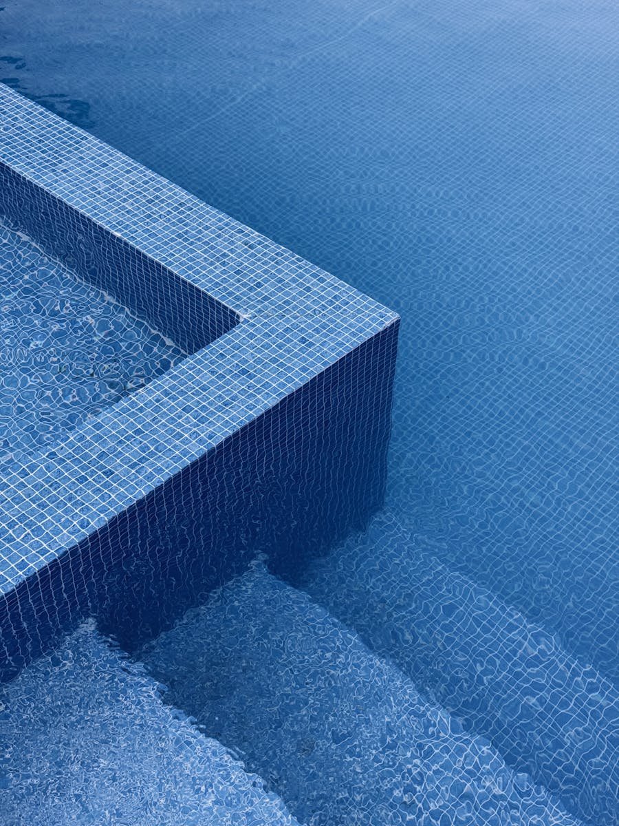 Rusnak Garden Felanitx - Abstract image of blue tiled pool edges with water ripples, exuding a minimalist and calming vibe.